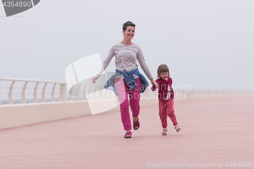 Image of mother and cute little girl on the promenade by the sea