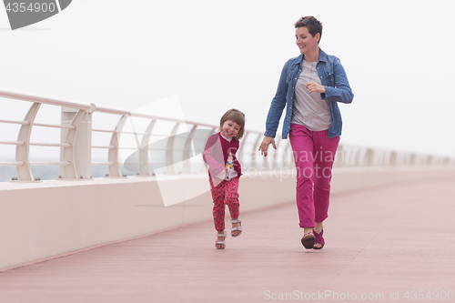 Image of mother and cute little girl on the promenade by the sea