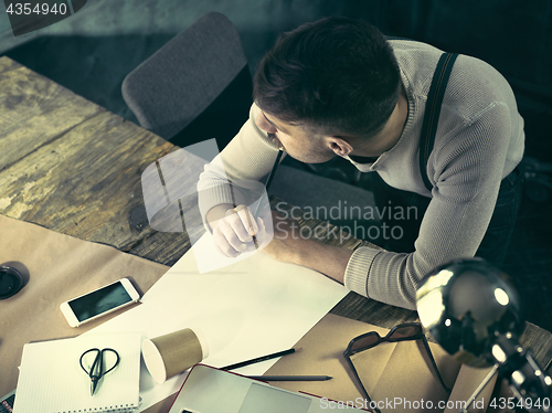 Image of Vintage hipster wooden desktop top view, male hands using a laptop and holding a pencil