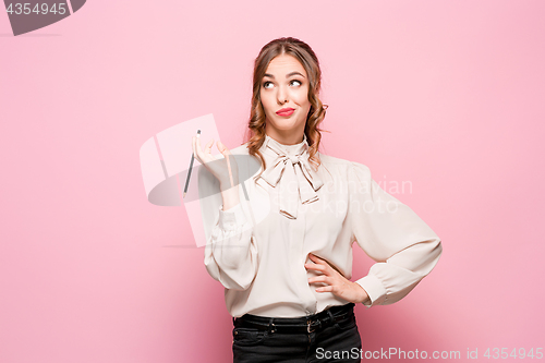 Image of The serious frustrated young beautiful business woman on pink background