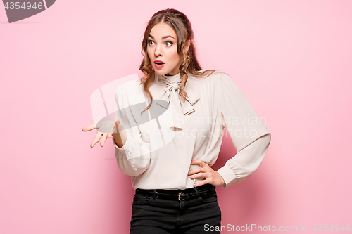 Image of The serious frustrated young beautiful business woman on pink background