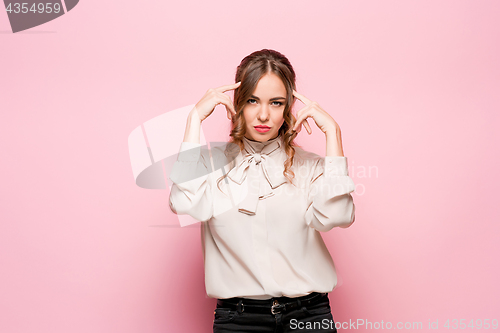 Image of The serious frustrated young beautiful business woman on pink background