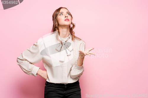 Image of The serious frustrated young beautiful business woman on pink background