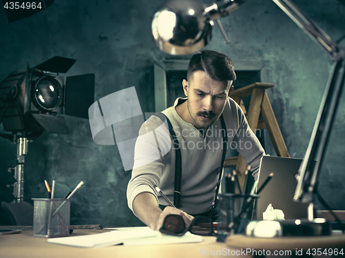 Image of Portrait of a bearded businessman who is checking details of his upcoming meeting in his notebook and typing.