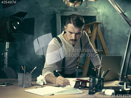 Image of Portrait of a bearded businessman who is checking details of his upcoming meeting in his notebook and typing.