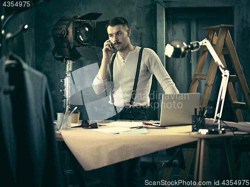 Image of Portrait of a bearded businessman who is working with his notebook at loft studio.