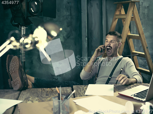 Image of Portrait of a bearded businessman who is working with his notebook at loft studio.