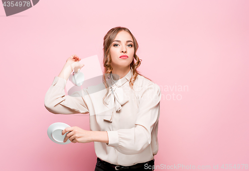 Image of The serious frustrated young beautiful business woman on pink background