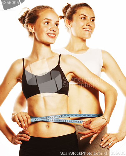 Image of two sport girls measuring themselves isolated on white