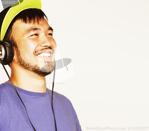 Image of young asian man in hat and headphones listening music on white b