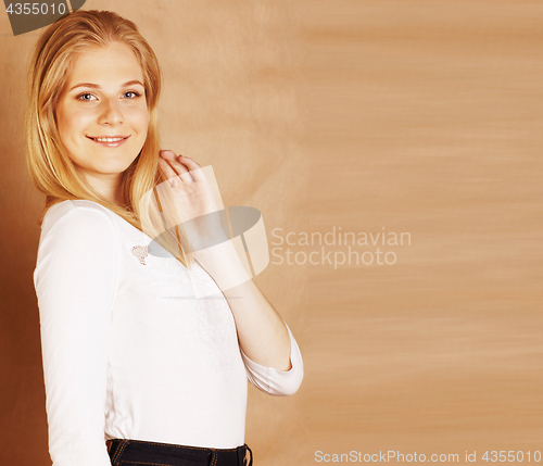 Image of young pretty blond woman happy cheerful smiling closeup on warm brown background, lifestyle real people concept copyspace