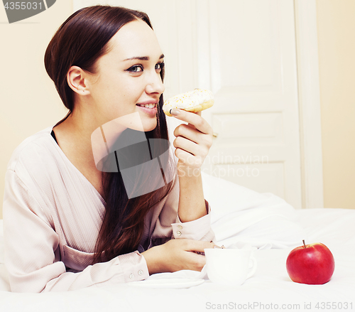 Image of young pretty brunette woman laying in bed, luxury white interior