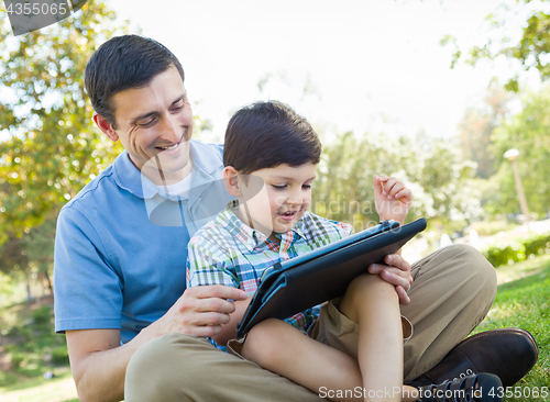 Image of Happy Father and Son Playing on a Computer Tablet Outside.