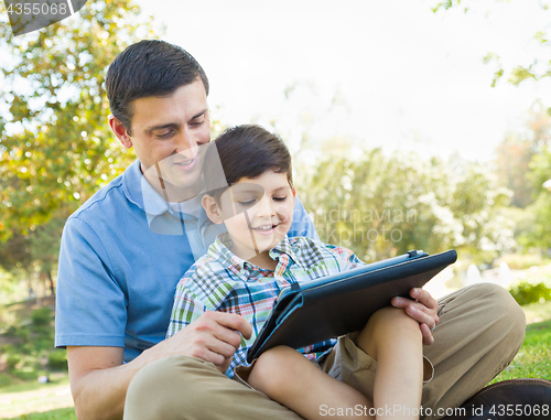 Image of Happy Father and Son Playing on a Computer Tablet Outside.