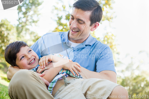 Image of Loving Young Father Tickling Son in the Park.