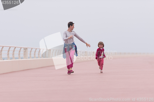 Image of mother and cute little girl on the promenade by the sea