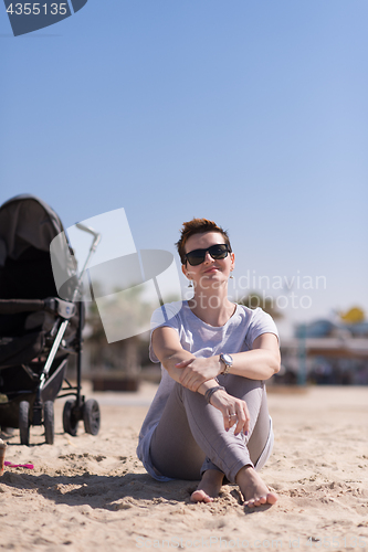 Image of Young mother with sunglasses relaxing on beach