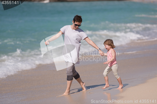 Image of mother and daughter running on the beach
