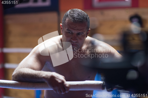 Image of kick boxer resting on the ropes in the corner