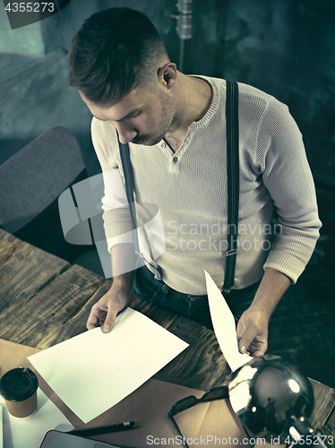 Image of Portrait of a bearded businessman who is checking details of his upcoming meeting in his notebook and typing.