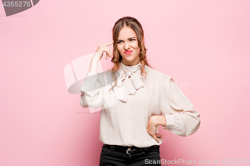 Image of The serious frustrated young beautiful business woman on pink background