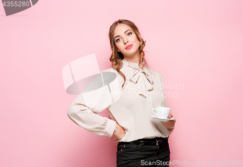 Image of The serious frustrated young beautiful business woman on pink background