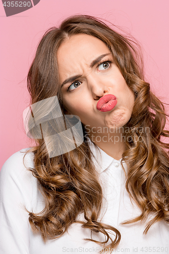 Image of Close-up portrait of a woman doing a fish mouth expression, over a pink background