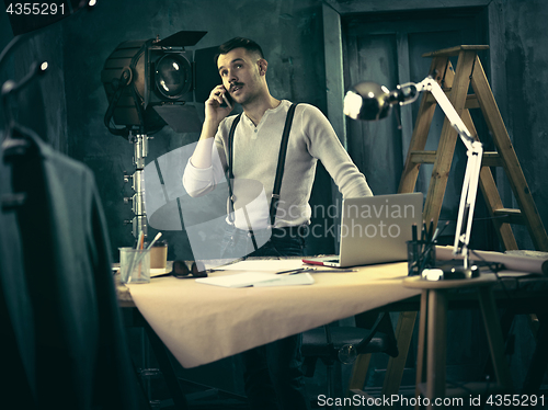 Image of Portrait of a bearded businessman who is working with his notebook at loft studio.