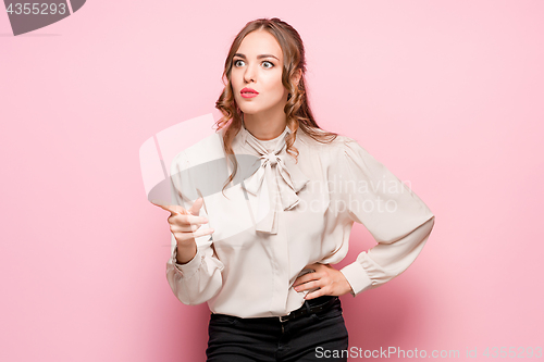 Image of The serious frustrated young beautiful business woman on pink background