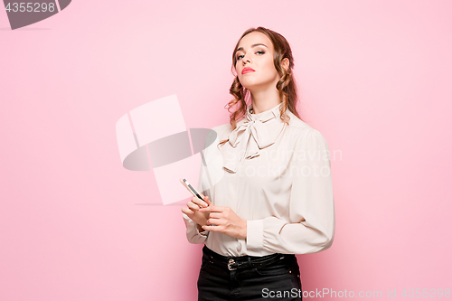 Image of The serious frustrated young beautiful business woman on pink background