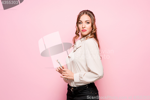 Image of The serious frustrated young beautiful business woman on pink background