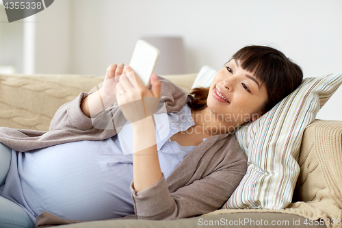 Image of happy pregnant woman with smartphone at home