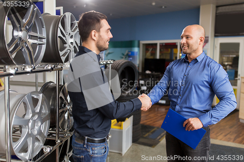 Image of auto business owner and wheel rims at car service