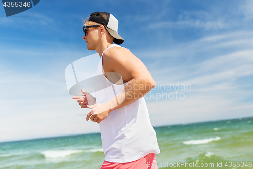 Image of happy man running along summer beach