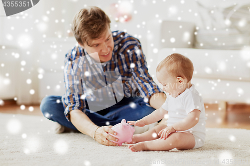 Image of happy father with baby and piggy bank at home