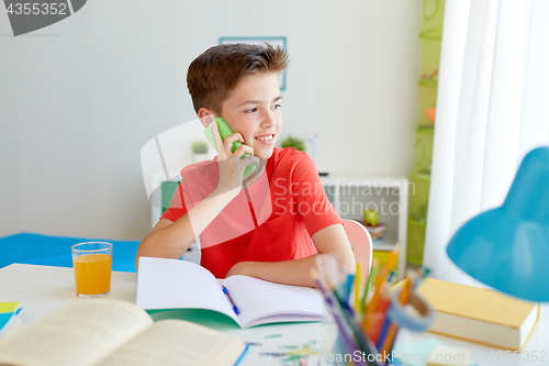 Image of student boy calling on smartphone at home