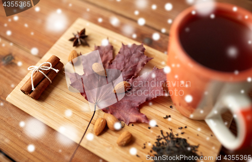 Image of cup of tea, maple leaf and almond on wooden board