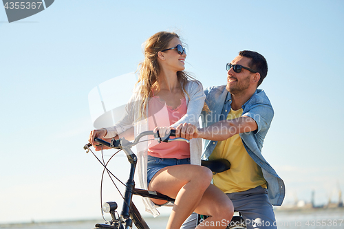 Image of happy young couple riding bicycle at seaside