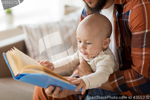 Image of happy father and little baby boy with book at home