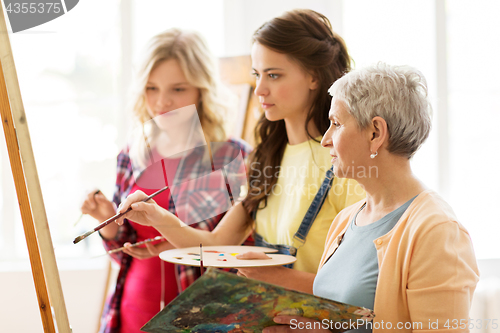 Image of women with easel and palettes at art school