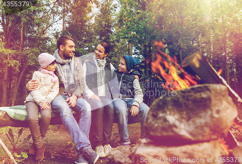 Image of happy family sitting on bench at camp fire