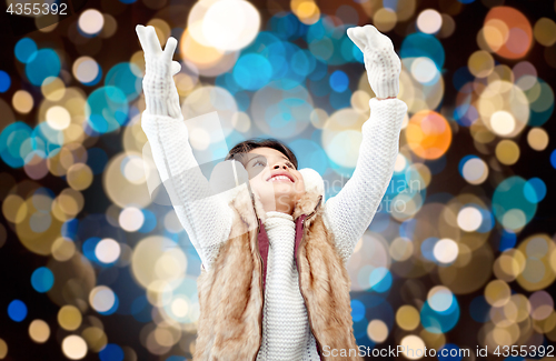 Image of happy girl in winter earmuffs over holidays lights