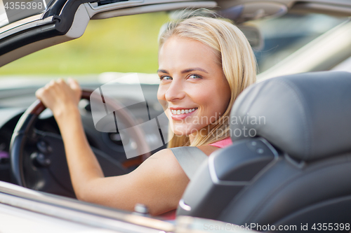 Image of happy young woman driving convertible car