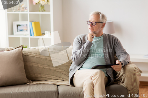 Image of senior man with tablet pc sitting on sofa at home