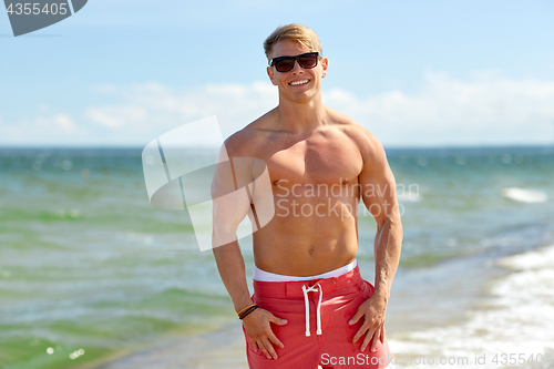 Image of smiling young man in sunglasses on summer beach