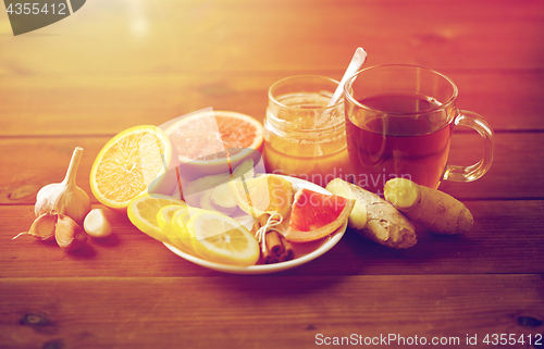 Image of ginger tea with honey, citrus and garlic on wood