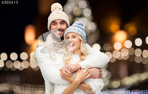 Image of happy couple hugging over christmas lights