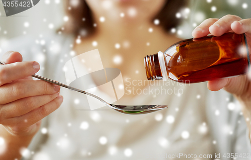 Image of woman pouring medication from bottle to spoon