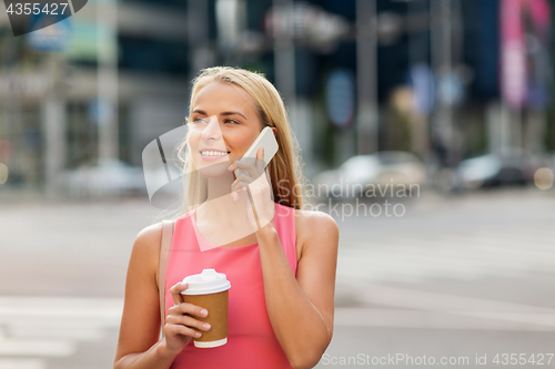Image of woman with coffee calling on smartphone in city
