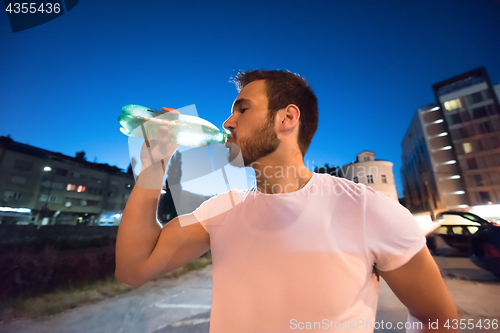 Image of man drinking water after running session